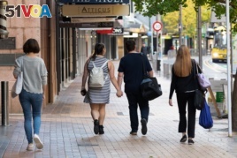 People walk down a street on the first day of the easing of restrictions in Wellington on April 28, 2020, following the COVID-19 coronavirus outbreak.