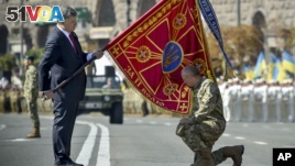 Ukraine's President Petro Poroshenko hands over a flag of a military unit on the occasion of Ukraine's Independence Day in the capital Kiev, Ukraine,  Monday, Aug. 24, 2015. Speaking at the parade, President Petro Poroshenko said Ukraine would continue to increase its troop numbers in order to fend off the attacks of separatist rebels.(AP Photo/Mykola Lazarenko, Pool)