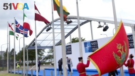Soldiers from Montenegro unfurl the national flag during a ceremony to mark the accession of Montenegro at NATO Headquarters in Brussels on Wednesday, June 7, 2017. 