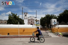 A man rides a bicycle past a church dome which collapsed in an earthquake is seen in Axochiapan, near Mexico City, Mexico September 29, 2017. REUTERS/Henry Romero