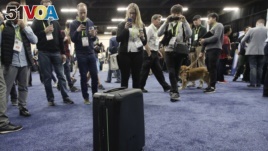 Attendees take pictures of ForwardX Robotics' CX-1 self-driving luggage during CES Unveiled at CES International Sunday, Jan. 7, 2018, in Las Vegas. (AP Photo/Jae C. Hong)