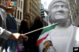Isabella Nordstrom waves an Italian flag near a large statue of Christopher Columbus before the Columbus Day Parade in New York on Oct. 14, 2013.  (AP Photo/Seth Wenig)