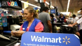 FILE - A cashier smiles beyond a Walmart logo during the kick-off of the 'El Buen Fin' (The Good Weekend) holiday shopping season, at a Walmart store in Monterrey, Mexico, November 17, 2017.