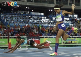 Bahamas' Shaunae Miller falls over the finish line to win gold ahead of United States' Allyson Felix, right, in the women's 400-meter final during the athletics competitions of the 2016 Summer Olympics at the Olympic stadium in Rio de Janeiro, Brazil, Mon