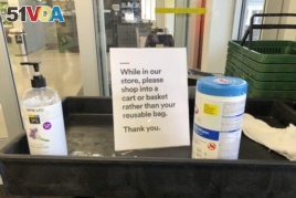 In this Sunday, March 29, 2020, photo, a sign posted at an entrance to a 365 Whole Foods store advises customers not to use their own bags while shopping in Lake Oswego, Ore. (AP Photo/Gillian Flaccus)