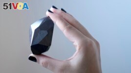 An employee of Sotheby's Dubai holds a 555.55 Carat Black Diamond called The Enigma. Photo taken at Sotheby's Dubai gallery in Dubai, United Arab Emirates, January 17, 2022. (AP Photo/Kamran Jebreili)