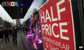 Christmas shoppers walk past a sale sign in the window of a shop in Oxford Street in London, Friday, Dec. 18, 2015. 