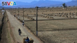 North Korean farmers pass along a road past farm fields at a collective farm near the town of Sariwon, North Korea.