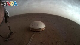 In this undated photo made available by NASA on Thursday, July 22, 2021, clouds drift over the dome-covered SEIS seismometer of the InSight lander on the surface of Mars. 