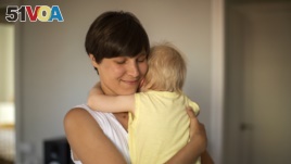 In this photo taken on Wednesday, June 19, 2019, Clara Massons holds her two years old son Jaume at her home in Barcelona, Spain. (AP Photo/Emilio Morenatti)