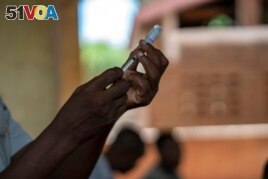 FILE - In this file photo taken Wednesday, Dec. 11, 2019, health officials prepare to vaccine residents of the Malawi village of Tomali, where young children become test subjects for the world's first vaccine against malaria.