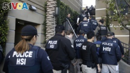 FILE - Federal agents enter an apartment complex where authorities say a birth tourism business charged pregnant women between $40,000 and $100,000 for lodging, food and transportation, in Irvine, Calif., March 3, 2015.