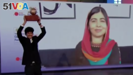 Sadat Rahman holds up his trophy prize as Malala Yousafzai cheers over video, during a ceremony on November 13 at The Hague.(Screenshot from Reuters video)