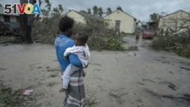 A woman and child near a school building being used as emergency shelter for some 300 local people who are unable to return to their homes following cyclone force winds and heavy rain in the coastal city of Beira, Mozambique, Sunday March 17, 2019.