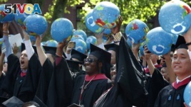 FILE - Public policy and government graduate students hold inflatable globes during Harvard University commencement exercises, Thursday, May 24, 2018, in Cambridge, Mass. (AP Photo/Michael Dwyer)