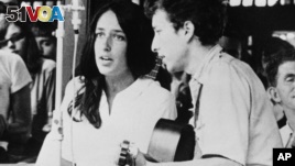FILE - In this 1963 file photo, Joan Baez and Bob Dylan perform at the Newport Jazz Festival in Newport, R.I. Two years later,  at the same festival, Dylan plugged in an electric guitar and shocked the music world.