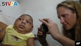 Pediatrician Alexia Harrist from the United States' Centers for Disease Control and Prevention (CDC) takes a picture of 3-month-old Shayde Henrique who was born with microcephaly, after examining him in Joao Pessoa, Brazil, Tuesday, Feb. 23, 2016.  In its
