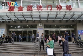 People walk past an entrance to Ruijin Hospital, Oct. 25, 2018, in Shanghai. Doctors at Ruijin have tried to turn the hospital into a center of deep brain stimulation research.