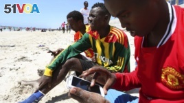 FILE - A Somali man browses the internet on his mobile phone at a beach in Somalia's capital Mogadishu, January 10, 2014.