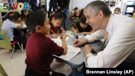 Education Secretary Arne Duncan visits with young student Mario Corona, age 6, in kindergarten at McGlone Elementary School in the Montbello section of Denver, in this May 14, 2015.