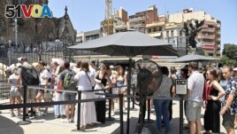 FILE - Tourist line up to enter at the Sagrada Familia basilica in Barcelona on July 18, 2023. (Photo by Pau BARRENA / AFP)