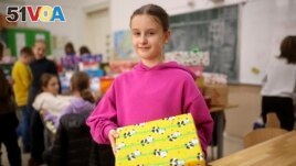 Sajra, 10, poses for a photo with a holiday present prepared for Ukrainian children inside Safvet Beg Basagic elementary school in Sarajevo, Bosnia, Tuesday, Dec. 20, 2022. (AP Photo/Armin Durgut)