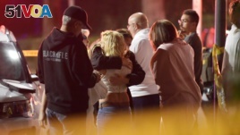 People comfort each other after a gunman opened fire Wednesday inside a country dance bar crowded with hundreds of people.