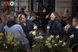 FILE - In this Wednesday, April 8, 2020 file photo people chat and drink outside a bar in Stockholm, Sweden. Sweden is pursuing relatively liberal policies to fight the coronavirus pandemic, even though there has been a sharp spike in deaths. (AP Photo/An