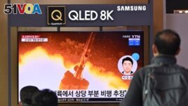 People watch a television screen showing a news broadcast with file footage of a North Korean missile test, at a railway station in Seoul on Jan. 25, 2022.