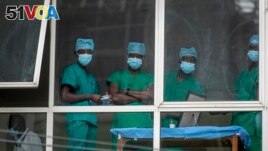 In this March 5, 2021, file photo, medical staff look out from a window as officials prepare for a ceremony to commence the country's first coronavirus vaccinations using AstraZeneca provided through the global COVAX initiative, at Kenyatta National Hospi