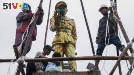 FILE - workers clean a vandalized statue of Myanmar independence hero Gen. Aung San, in Myitkyina, capital of Kachin state, Myanmar, July 23, 2018.