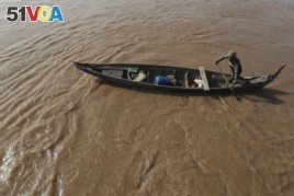 FILE - A Cambodian Muslim man rows his wooden boat where he lives along the Mekong River bank at a fisherman floating village located in Kball Chroy, near Phnom Penh, Cambodia, on Monday, Sept. 9, 2019. (AP Photo/Heng Sinith)