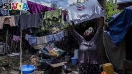 Mother of two Amsale Hailemariam, a domestic worker who lost work because of the coronavirus, hangs clothes after washing them outside her small tent in the capital Addis Ababa, Ethiopia on Friday, June 26, 2020. (AP Photo/Mulugeta Ayene)