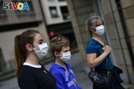 A family wearing face mask to protect of the coronavirus go for a walk, in Pamplona, northern Spain, Sunday, April 27, 2020. On Sunday, children under 14 years old will be allowed to take walks with a parent for up to one hour.
