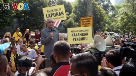 Malaysia's opposition coalition prime ministerial candidate Mahathir Mohamad speaks against a controversial proposal to redraw electoral boundaries outside near the Parliament House in Kuala Lumpur, Malaysia March 28, 2018. The sign (front R) reads: 