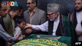 Ten year-old Mustafa, son of Afghan reporter Zabihullah Tamanna,(2L), relatives and friends pray around the coffin during a ceremony at a military hospital in Kabul on June 7, 2016. 
