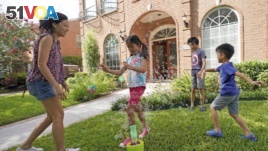Vicky Li Yip sets up a bubble machine for her children, L to R, Kelsey, 8, Toby, 10 and Jesse, 5, outside their home, July 10, 2020 in Houston. She works from home and says online schooling has been exhausting, even with her husband helping out. (AP Photo/David J. Phillip)