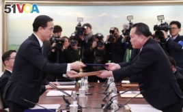 Head of the North Korean delegation, Ri Son Gwon exchanges documents with South Korean counterpart Cho Myoung-gyon after their meeting at the truce village of Panmunjom