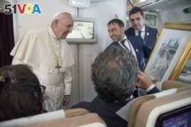 Pope Francis receives a gift from a journalist during his flight from Abu Dhabi to Rome, Tuesday, Feb. 5, 2019. Pope Francis has concluded his historic visit to the Arabian Peninsula with the first-ever papal Mass in the birthplace of Islam.