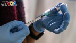 An employee from the National Health Organization (EODY) prepares a Johnson and Johnson vaccine against COVID-19 at Karatepe refugee camp, on the northeastern Aegean island of Lesbos, Greece, on December 15, 2021. (AP Photo/Panagiotis Balaskas, File)
