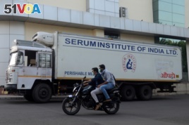 Men ride on a motorbike past a supply truck of India's Serum Institute, the world's largest maker of vaccines, which is working on a vaccine against the coronavirus disease (COVID-19) in Pune, India, May 18, 2020