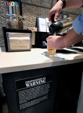 In this Sept. 22, 2017, file photo, a customer pours milk into coffee near a posted Proposition 65 warning sign at a Starbucks coffee shop in Los Angeles. (AP Photo/Richard Vogel)