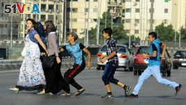 FILE - In this Aug. 20, 2012 file photo, an Egyptian youth, trailed by his friends, gropes a woman crossing the street with her friends in Cairo, Egypt. (AP Photo/Ahmed Abd El Latif, El Shorouk Newspaper, File)