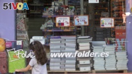 A young girl wearing a face mask walks past a store displaying a coronavirus information poster and selling children's school stationery, backpacks, protective masks and hand sanitizers in Madrid, Spain, Monday, Aug. 24, 2020.