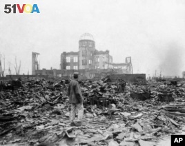 This Sept. 8, 1945 picture shows an allied correspondent standing in the rubble in front of the shell of a building that once was a movie theater in Hiroshima, Japan, a month after the first atomic bomb ever used in warfare. President Barack Obama will visit Hiroshima later this month. (AP Photo/Stanley Troutman)