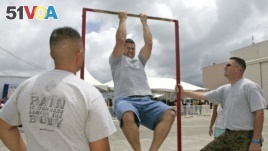 FILE - Matt Elam, center, competes in a US Marine pull-up contest while Marine recruiters Sgt. Marco Hartanto, left, and Gysgt. Brian Lancioni watch during BayFest 2006 held at Marine Corps Base Hawaii, Tuesday, July 4, 2006, in Kaneohe, Hawaii.