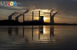 In this June, 3, 2017, file photo, the sun sets behind Georgia Power's coal-fired Plant Scherer, one of the nation's top carbon dioxide emitters, in Juliette, Ga. (AP Photo/Branden Camp, File)