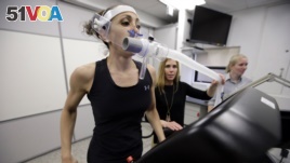 In this April 23, 2019 photo, research scientist Leila Walker, left, is assisted by nutritional physiologist Holly McClung, center, as they demonstrate equipment designed to evaluate fitness levels in female soldiers who have joined elite fighting units.