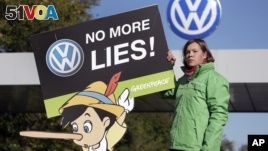 An activist with the environmental group Greenpeace protests Volkswagen emissions rigging. She stands outside a VW factory in Wolfsburg, Germany.