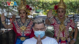  A man wearing a face mask pray at Erawan shrine as traditional dancers preform in Bangkok, Thailand, Wednesday, Jan. 29, 2020.